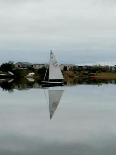 a sail boat on the water with a city in the background at The Patch at Snettisham Beach in Snettisham