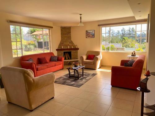 a living room with red couches and a fireplace at Las Hortensia's Casa De Huespedes in Tababela