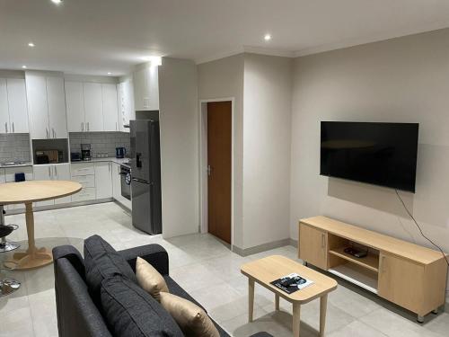 a living room with a couch and a flat screen tv at Biz & Bliss Work & Serene Views in Windhoek