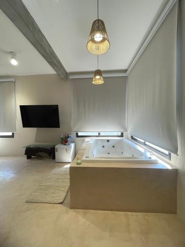 a large room with a tub and a tv at Refúgio na Natureza com hidro - Mariscal 09 in Bombinhas