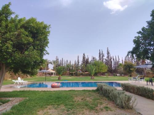 a swimming pool in the middle of a park at Appartement 2 chambres en ferme avec Piscine Privée in Marrakech