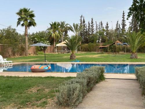 a swimming pool in a yard with palm trees at Appartement 2 chambres en ferme avec Piscine Privée in Marrakech
