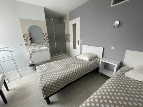 a bedroom with two beds and a bathroom with a sink at La Mansardière in Cancale