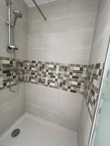 a bathroom with a shower with a toilet and tiles at La Mansardière in Cancale