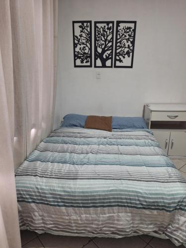 a bed in a bedroom with two pictures on the wall at Studio Nerd em Floripa in Florianópolis