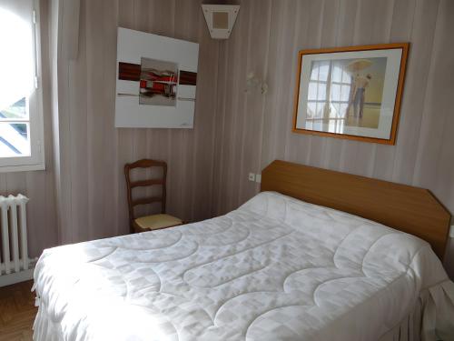 a bedroom with a large white bed and a chair at La Mansardière in Cancale