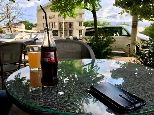 Una botella de Coca-Cola y un teléfono móvil sobre una mesa. en Propriete Ten, en Iaşi