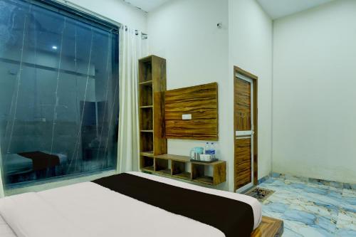 a bedroom with a bed and a large window at Hotel O The Suresh Mahal Resort in Jaipur