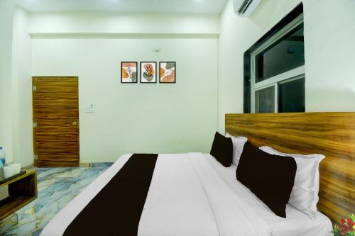 a bedroom with a white bed with black and white pillows at Hotel O The Suresh Mahal Resort in Jaipur