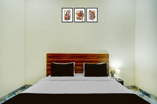a bedroom with a white bed with a wooden headboard at Hotel O The Suresh Mahal Resort in Jaipur