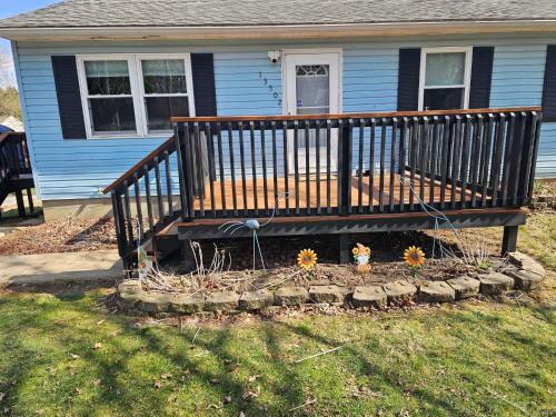 a porch of a house with flowers in a yard at Blue Cottage with Game Room Deck & Hot Tub in Logan