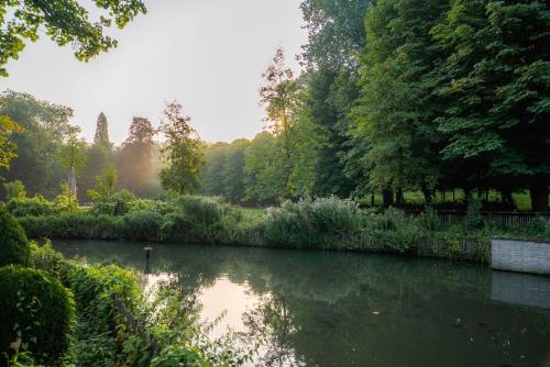 a view of a pond in a park with trees at Vakantie Logies de Kleine Motte in Sint-Truiden
