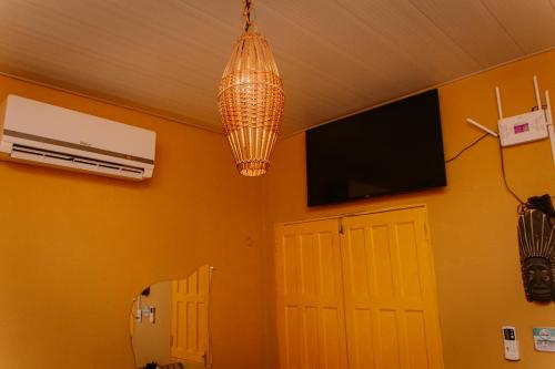 a room with a chandelier and a television and a door at Casinha No Beco do Amor 80mts praia in Alter do Chao