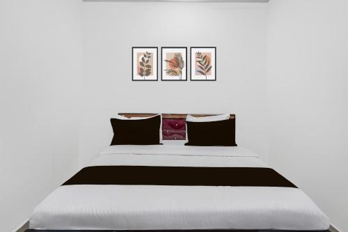 a bedroom with a large bed with three pictures on the wall at Hotel O Sushant Hotels NSEZ Metro Station in Sūrajpur