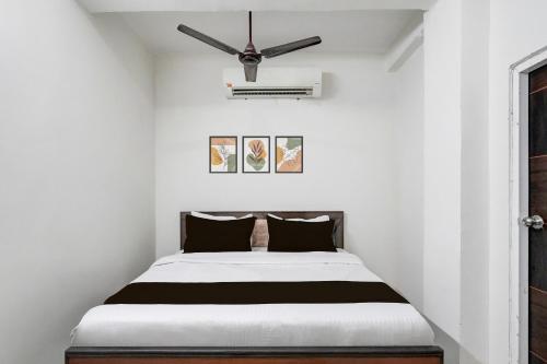 a bed in a white room with a ceiling fan at Hotel O Sushant Hotels NSEZ Metro Station in Sūrajpur