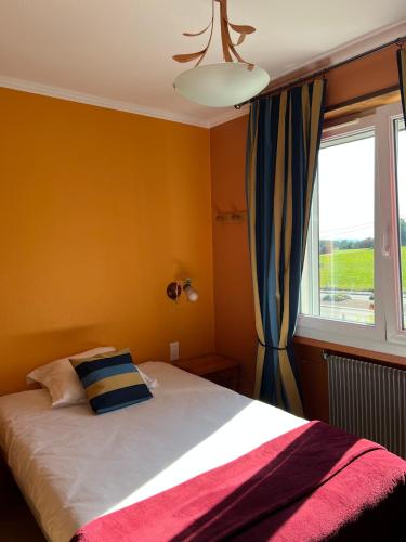 a bedroom with a large bed with a window at Hôtel l'Orée des Roches in Saales