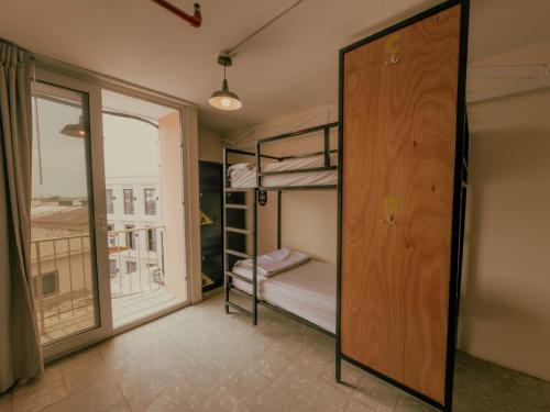 a room with bunk beds and a door with a window at Viajero Casco Viejo Hostel in Panama City