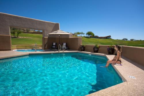 a woman is sitting on the edge of a swimming pool at Inn at Eagle Mountain in Scottsdale