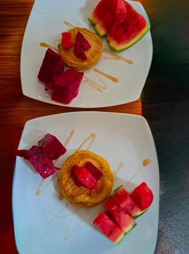 two plates of food with watermelon and crackers on them at Lonthar B&B - Adults Only in Riung