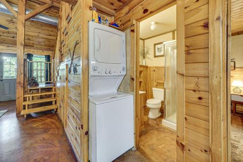 a large white refrigerator in a room with wooden walls at 3 Mi to Beavers Bend State Park Hot Tub Hideaway! in Broken Bow