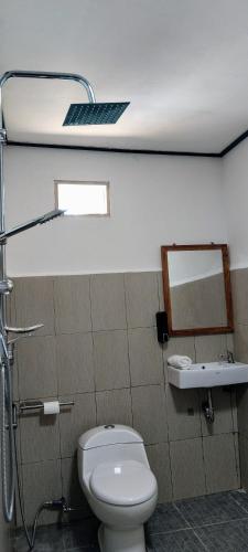 a bathroom with a toilet and a sink and a mirror at Lonthar B&B - Adults Only in Riung