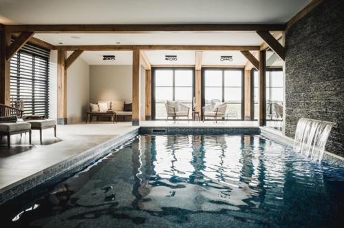 a large swimming pool in a house with a living room at Luxe Poolhouse Ouddorp in Ouddorp