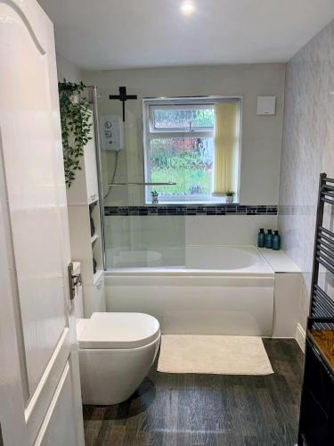 a bathroom with a tub and a toilet and a window at Cosy home in Walsall in Bloxwich