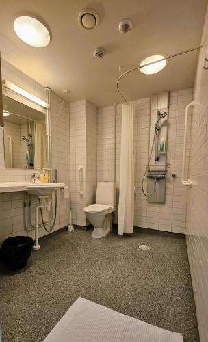 a bathroom with a toilet and a sink and a shower at Hotelli Sammatti in Lohja