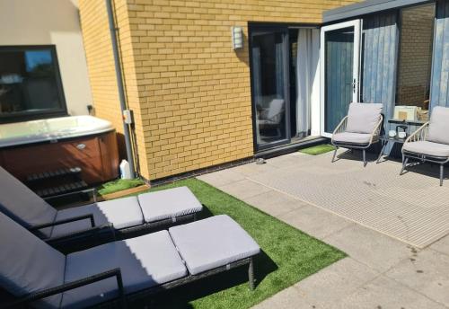 a patio with two chairs and a couch on the grass at The Snuggery-Hot Tub-Parking-Eco in Topsham