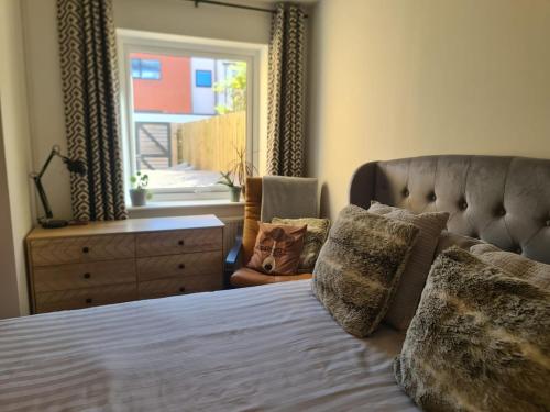 a bedroom with a bed and a dresser and a window at The Snuggery-Hot Tub-Parking-Eco in Topsham