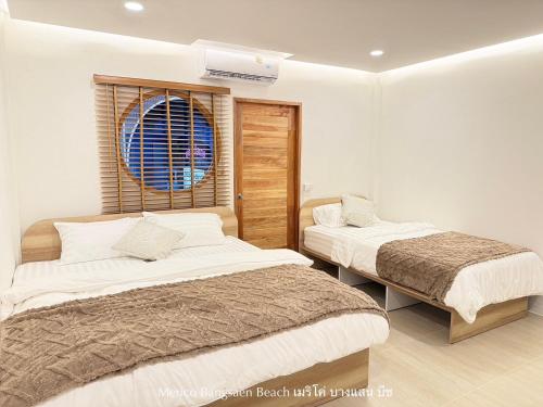 ein Schlafzimmer mit zwei Betten und einem Fenster in der Unterkunft เมริโค่ บางแสน บีช Merico Bangsaen Beach in Ban Laem Thaen