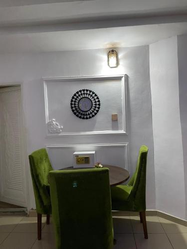 a dining room with a table and green chairs at 501 Aparthotel in Akure