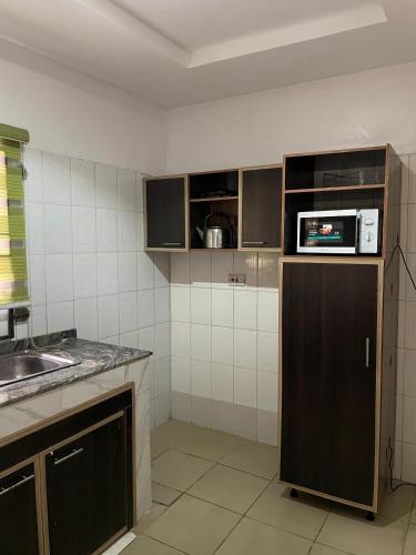 a kitchen with a microwave on top of a refrigerator at 501 Aparthotel in Akure