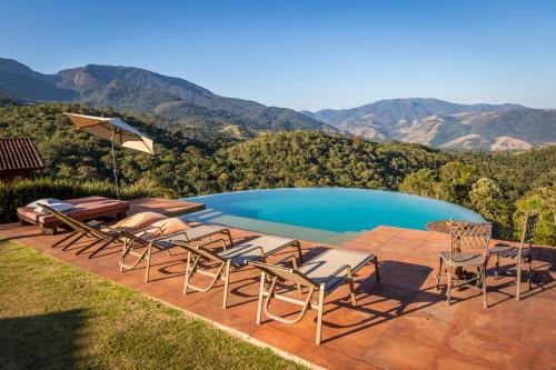 a group of chairs and a swimming pool with mountains in the background at Chácara da Mantiqueira - São Francisco Xavier in São José dos Campos