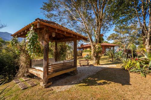 a wooden gazebo with a bench in a yard at Chácara da Mantiqueira - São Francisco Xavier in São José dos Campos