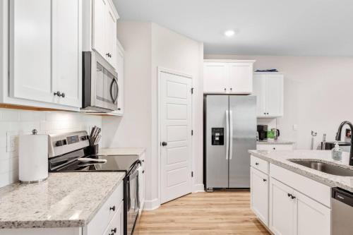 a kitchen with white cabinets and a stainless steel refrigerator at Spacious 4BR Home Near Midtown & FSU in Saint Peter