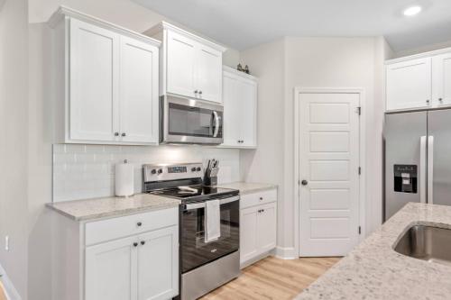 a kitchen with white cabinets and a stove top oven at Spacious 4BR Home Near Midtown & FSU in Saint Peter