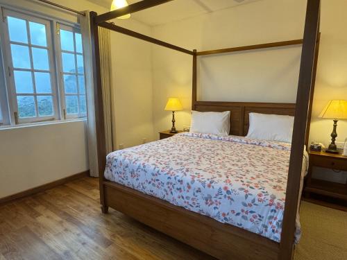 a bedroom with a canopy bed and two windows at The Mountain Links, Upcot, Nuwara Eliya in Maskeliya