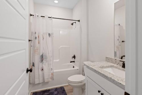 a white bathroom with a toilet and a sink at Spacious 4BR Home Near Midtown & FSU in Saint Peter