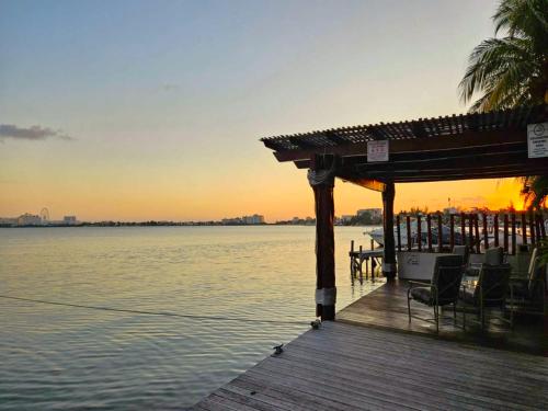 a wooden dock with chairs on the water at sunset at SINA SUITES CANCUN - Adults Only in Cancún
