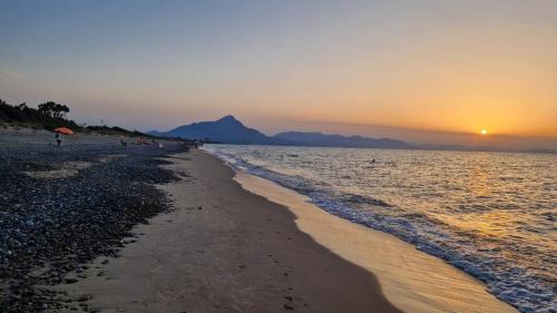 a beach with the sun setting over the water at a due passi dal mare in Campofelice di Roccella