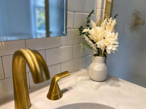 a bathroom sink with a vase of flowers and a gold faucet at Serenity Haven - A Modern Retreat in Monroe