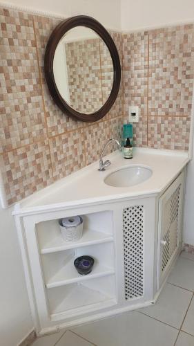 ein Badezimmer mit einem weißen Waschbecken und einem Spiegel in der Unterkunft Suítes da Rua Belica in Tiradentes