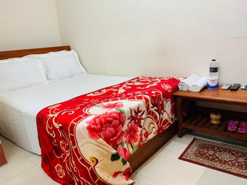 a bedroom with a bed with a red and white blanket at Hotel Rose Garden Palace Residential in Dhaka