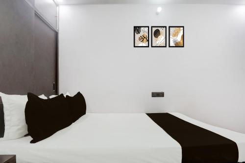 a bedroom with a white bed with black pillows at Hotel O Swarun and Banquet Hall in Gulzārbāgh