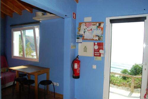 a room with a blue wall with a table and a fire extinguisher at Arrifana - CASA DAS MARÉS - Casa na Praia in Aljezur