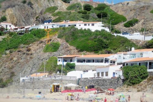 a group of buildings on a hill with a beach at Arrifana - CASA DAS MARÉS - Casa na Praia in Aljezur