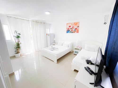 a white living room with two beds and a desk at CARIBBEAN SEA Hotel BEACH Vacation rental studios LONG TERM POOL SPA in Punta Cana