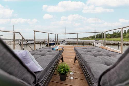 a balcony with couches on a dock with the water at Hausboot MeerZeit an der Ostsee in Stralsund