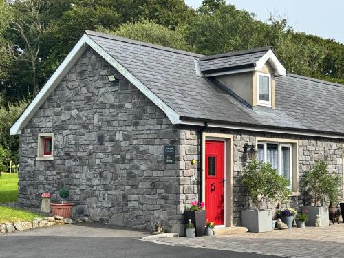 a small stone building with a red door at The Beehive at Pudding Cottage in Seapatrick